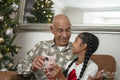 Senior man with granddaughter looking at smart phone at Christmas tree