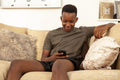 Teenage boy sitting on sofa and using phone