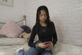 Teenage girl using smart phone on bed at home