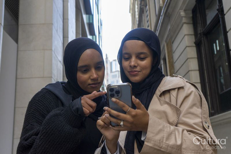Two young women in city, looking at phone