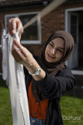 Woman wearing hijab hanging laundry in backyard