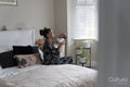 Mother carrying newborn baby girl while sitting on bed at home