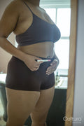 Mid section of woman holding pregnancy test in front of belly