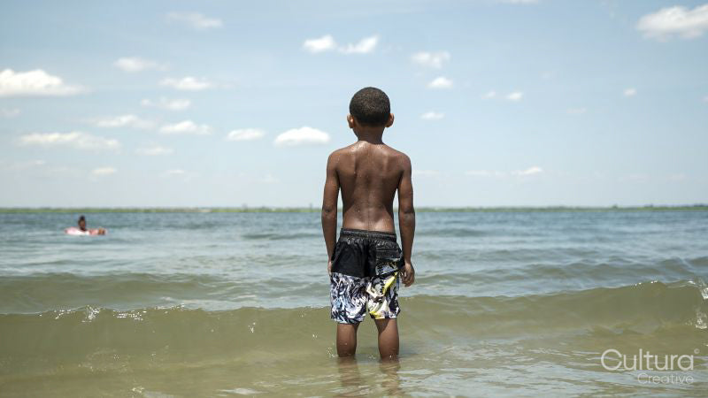 Rear view of boy standing in sea