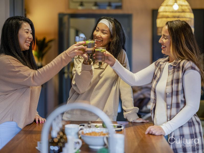 Female friends making celebratory toast in kitchen