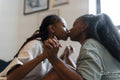couple kissing while holding hands at home