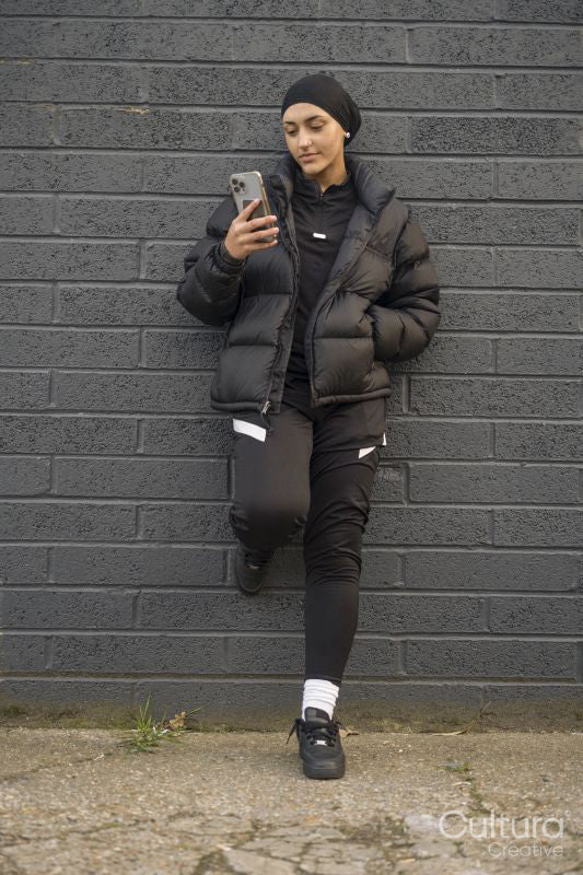 Young woman leaning on wall and using smartphone