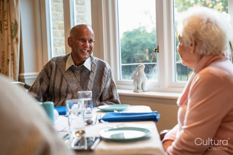 Senior people talking at table during meal in nursing home