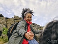 Woman helping fellow hiker climb rocky mountain
