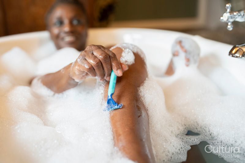 Senior woman taking bubble bath and shaving legs