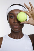 Studio portrait of athletic woman with tennis ball