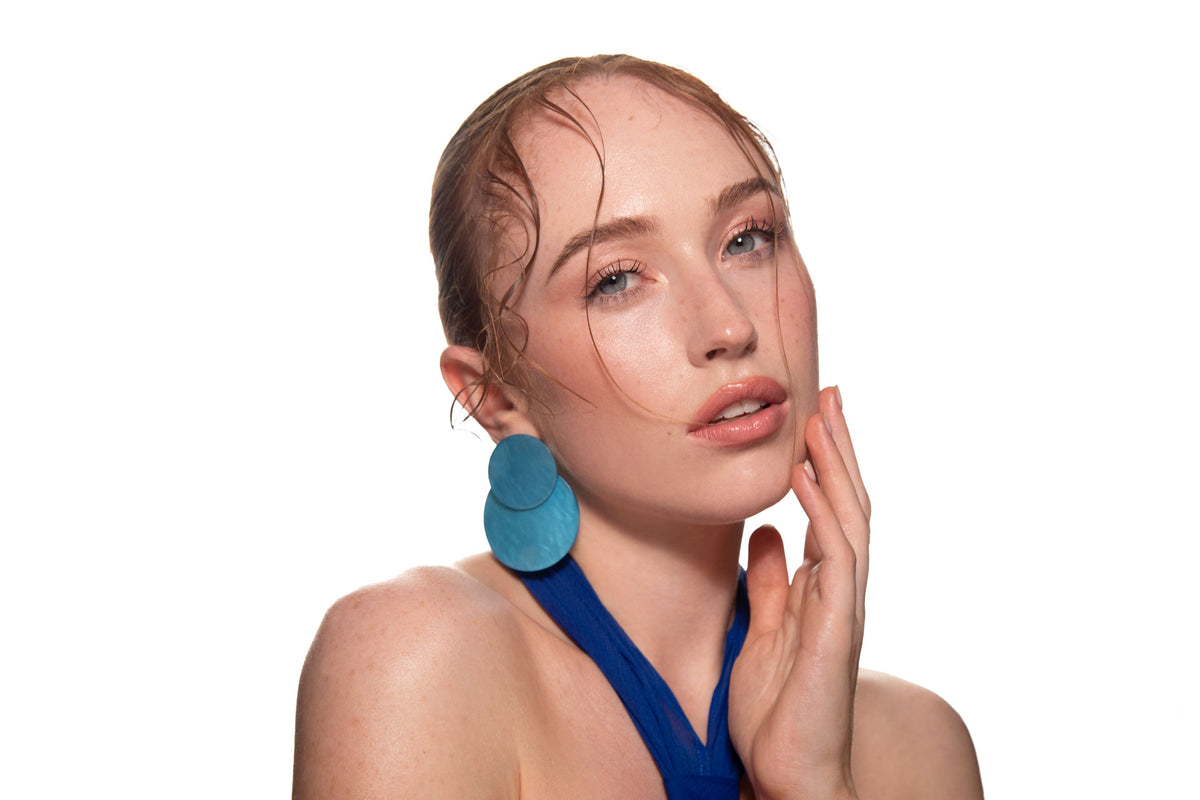 Studio portrait of a woman in a blue dress and large blue earrings