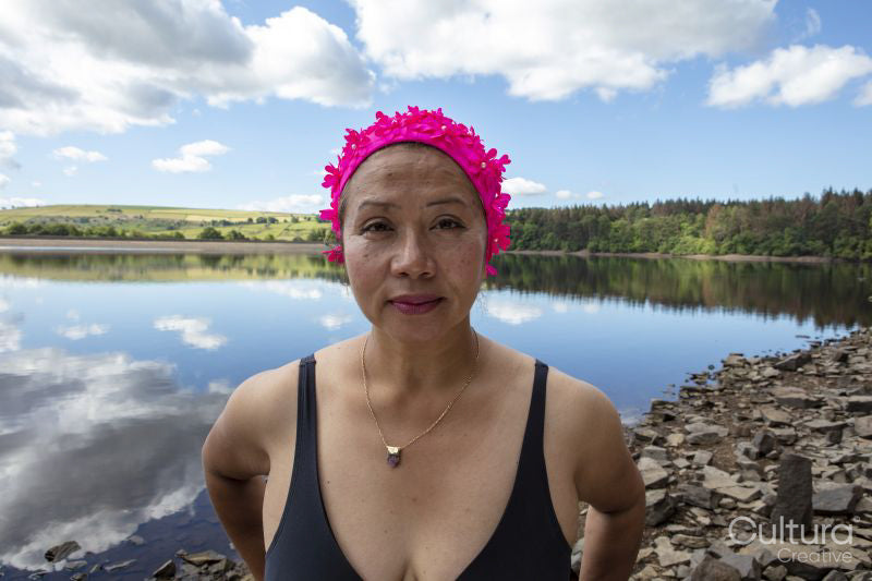 Portrait of woman in pink swimming cap and swimsuit on lakeshore, Yorkshire, UK