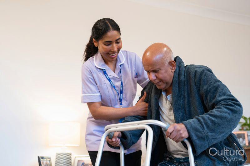 Nurse helping senior man to stand up with mobility walker at nursing home