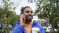 Young man holding coffee and talking on phone