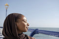 Portrait of Muslim woman with closed eyes by sea on sunny day