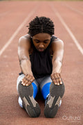 Athletic woman stretching legs on running track