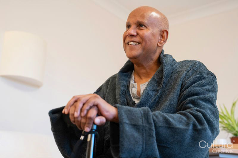 Senior man sitting on bed in room at nursing home