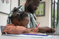 Father using laptop and daughter drawing in notepad