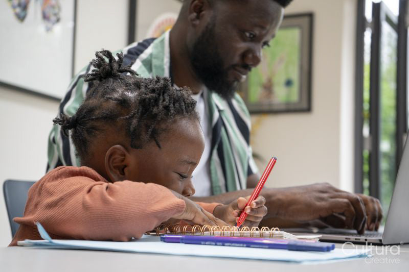 Father using laptop and daughter drawing in notepad