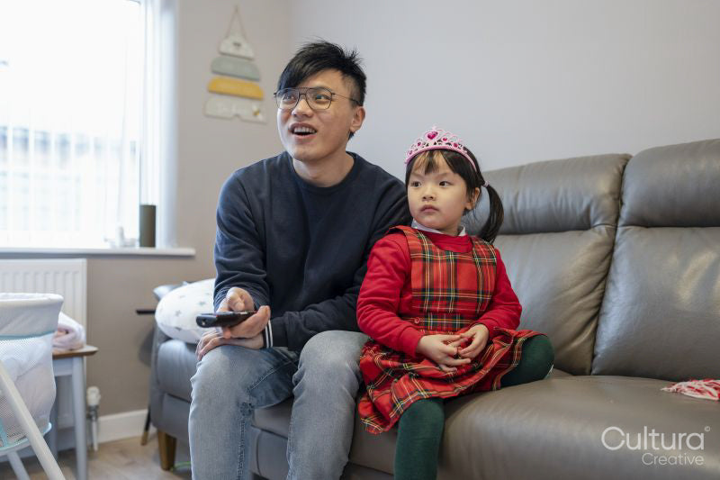 Father sitting with daughter on sofa and watching TV