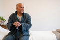 Senior man sitting on bed in room at nursing home