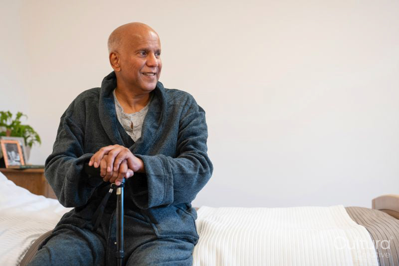 Senior man sitting on bed in room at nursing home