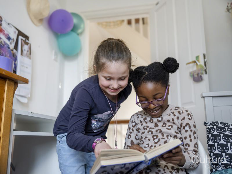 Girl friends reading book at home