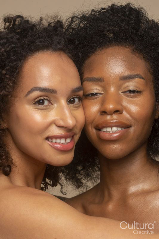 Studio portrait of two smiling women cheek to cheek