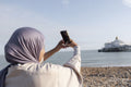 Muslim woman taking selfie by sea on sunny day
