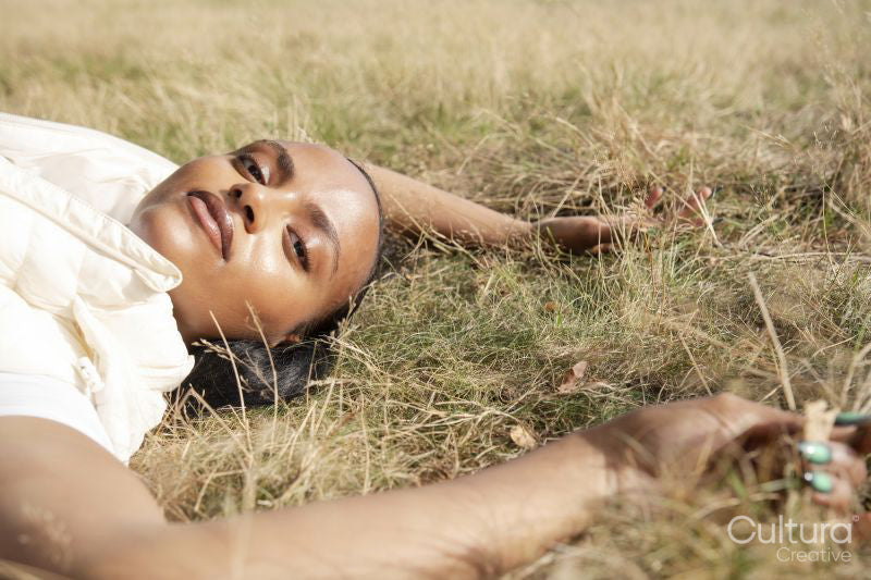Portrait of young woman lying in grassy field