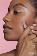 Young woman using face massager