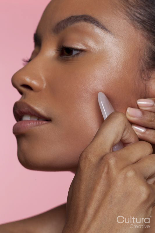 Young woman using face massager