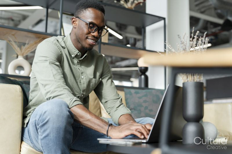Young man with laptop sitting in office lounge
