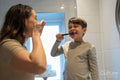 Mother and son brushing teeth together
