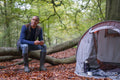 Man using smart phone while camping in forest at autumn