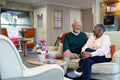 Smiling senior man and woman sitting on sofa in nursing home