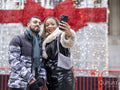 Young couple taking selfies against Christmas decorations