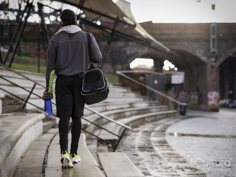 Rear view of athletic man with gym bag walking outdoors