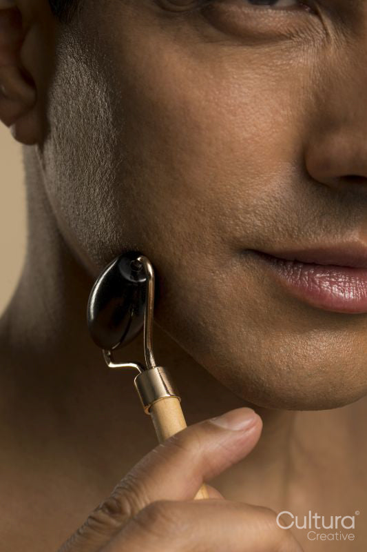 Close-up of man using face roller