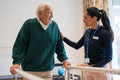 Female therapist assisting senior man walking on bars in exercise room