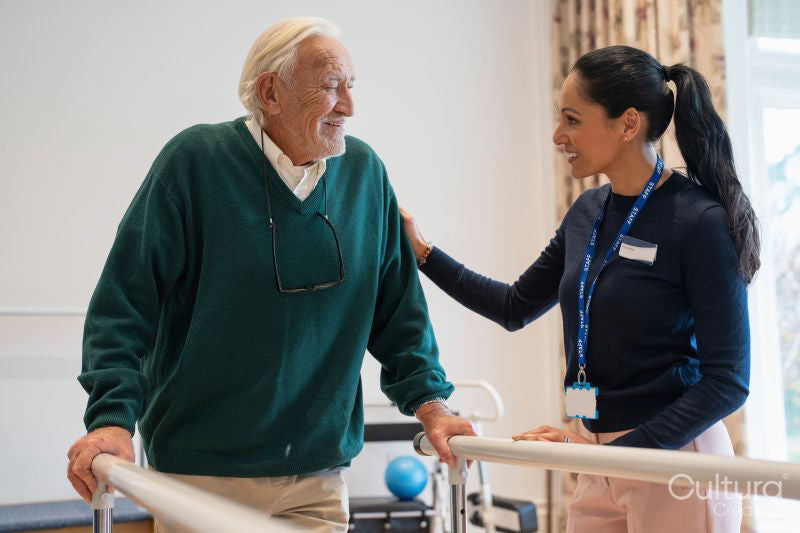 Female therapist assisting senior man walking on bars in exercise room