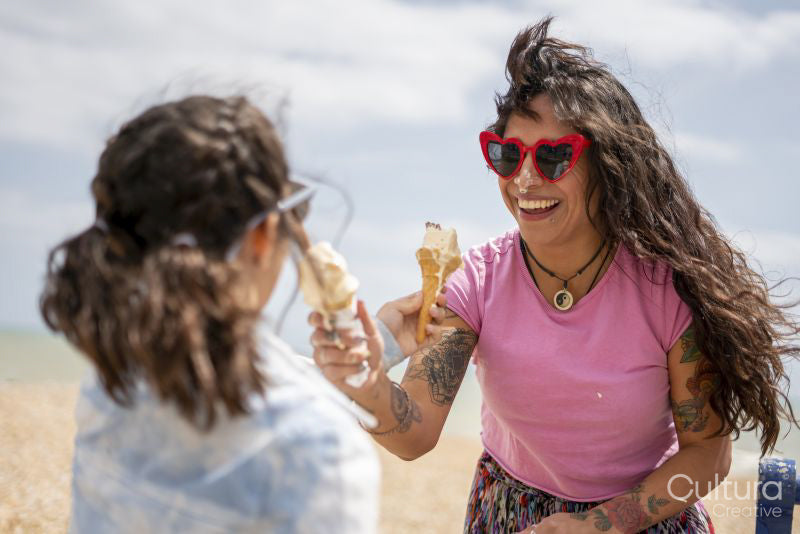 Mother and daughter eating ice cream on beach
