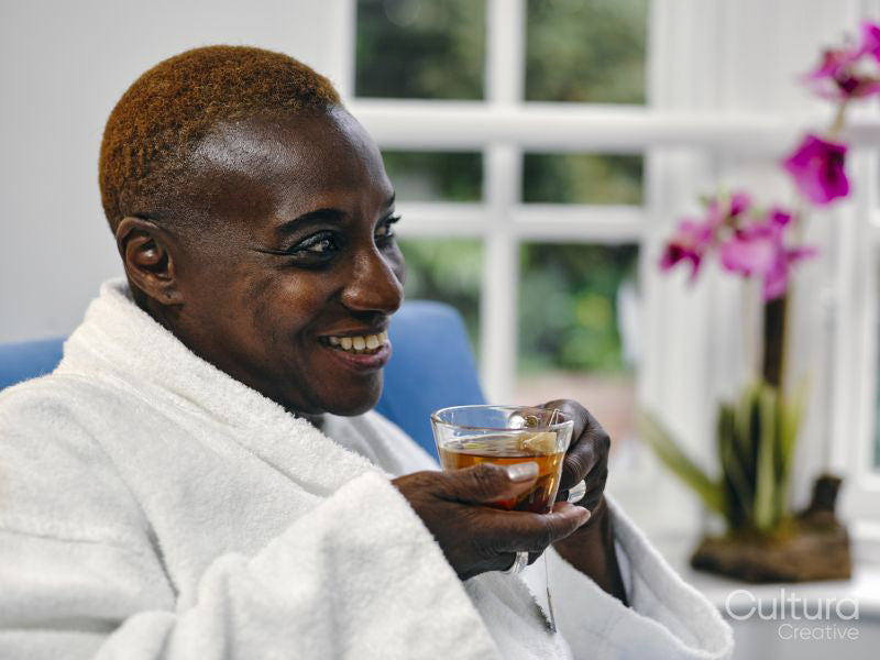Mature woman in white bathrobe enjoying tea