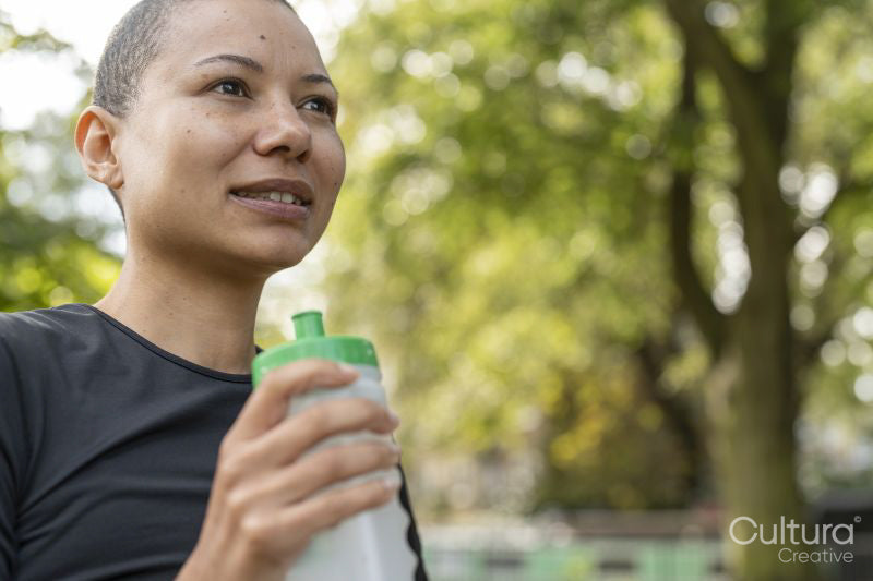 Athletic woman holding water bottle in park