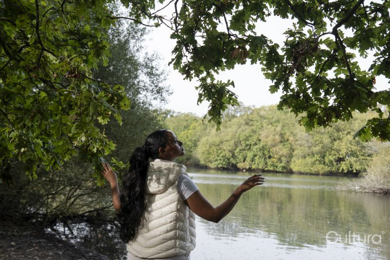 Rear view of woman standing by river with arms raised