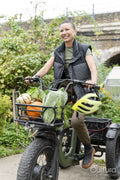 Smiling woman riding cargo electric trike loaded with homegrown vegetables