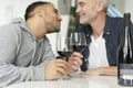 Male couple drinking red wine and kissing at home