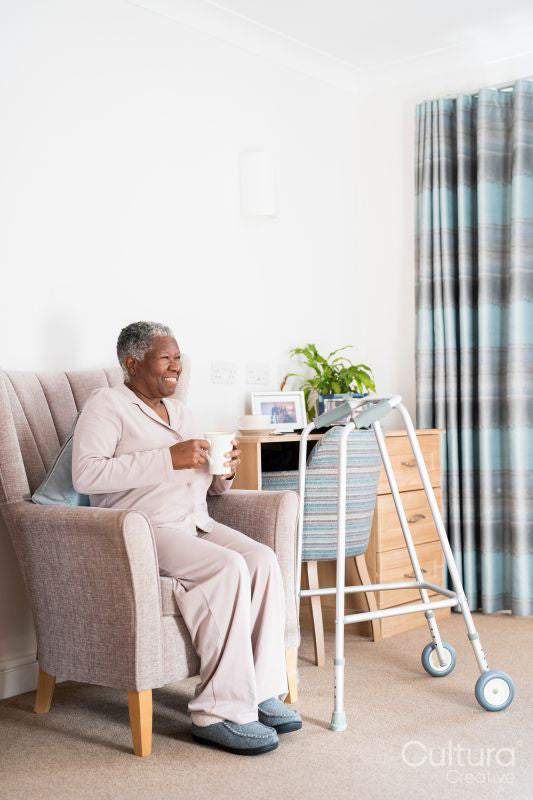 Smiling senior woman sitting in armchair, holding mug