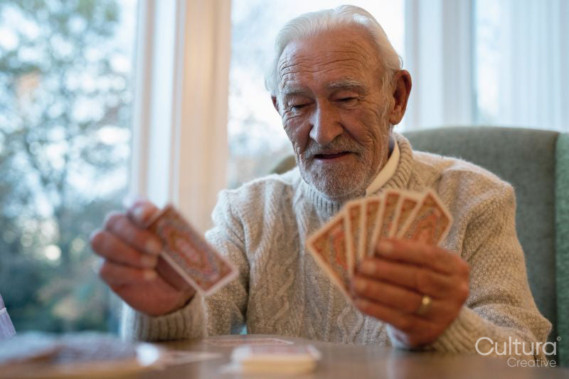 Senior man playing cards at table